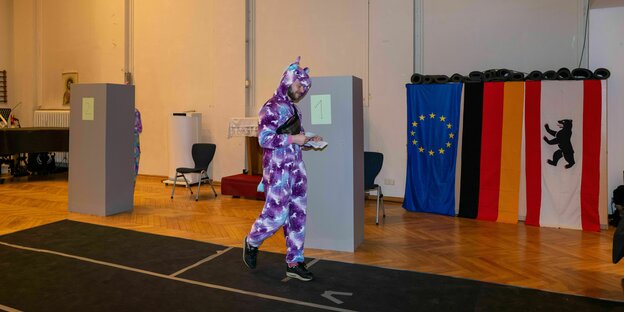 Eine als lila Einhorn verkleidete Person in einem Wahllokal