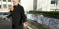 Franz-Josef Overbeck, Bischof des Bistums Essen, spricht vor Protestplakaten gegen Missbrauch in der katholischen Kirche zu Journalisten