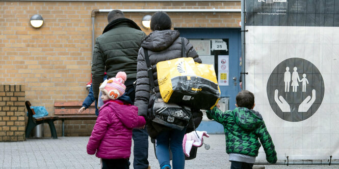 Eine Familie, gesehen von hinten, geht auf ein Haus zu