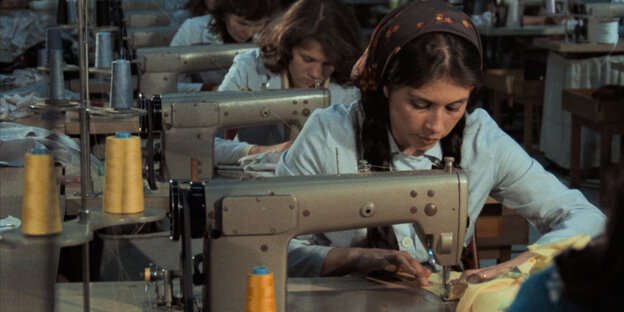 In einer langen Reihe sitzen Arbeiterinnen an Nähmaschinen hintereinander