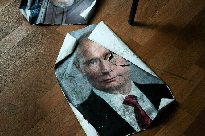 Ein schmutziges und zerknittertes Plakat mit dem Porträt von Putin liegt auf dem Boden