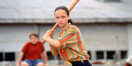 Eine junge Frau holt mit einem Baseballschläger aus