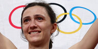 Eine Frau weint, hinter ihr ist das Logo der olympischen Spiele zu sehen
