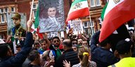 Demonstration mit Schildern und iranischen Flaggen