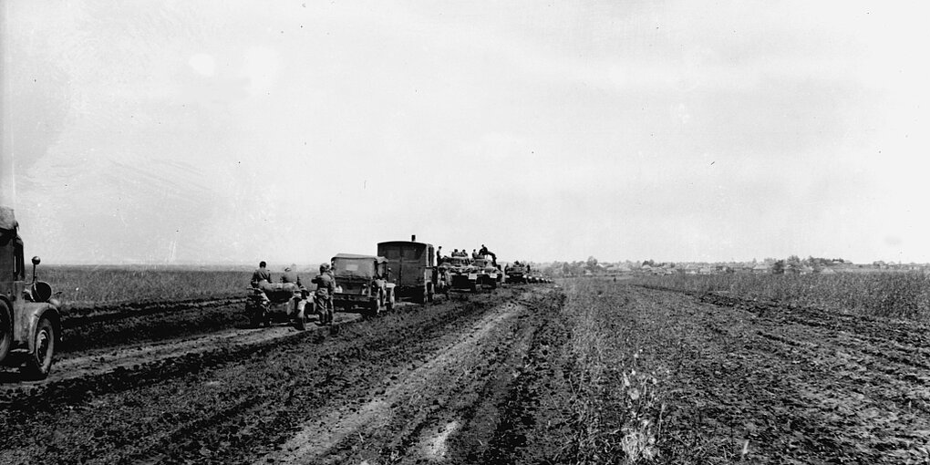 Wehrmachtssoldaten mit Kriegsfahrzeugen in weiter Landschaft