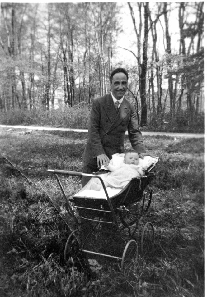 Kurt Huber steht lächelnd an einem Kinderwagen, der auf einer Wiese steht