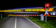 Ein Zug fährt in der Dunkelheit an einem Bahnübergang vorbei