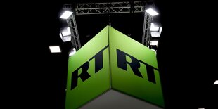 Ein beleuchteter Messeaufbau mit Werbetafel, Aufschrift: „RT“