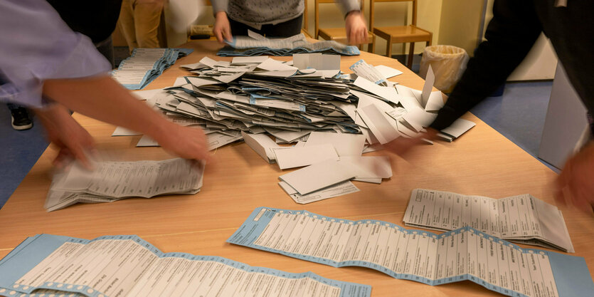 Das Foto zeigt einen Tisch voller Wahlzettel.