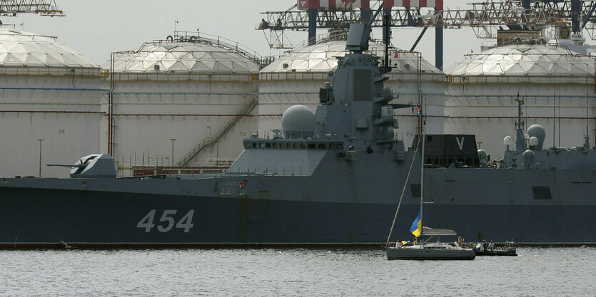 Ein Segelboot mit ukrainischer Flagge vor einem Kriegsschiff