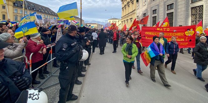 Anti-Siko- ziehen an Pro-Ukraine-Demonstranten vorbei, dazwischen steht die Polizei