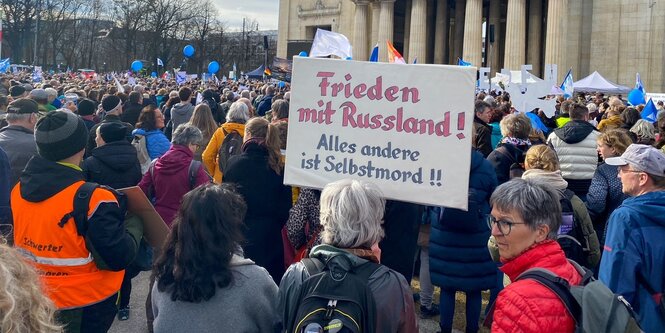 Frau hält Transparent mit der Aufschrift "Frieden mit Russland. Alles andere ist Selbstmord!!"