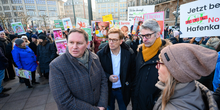 Der Hamburger Kultursenator Carsten Brosda steht vor Demonstrierenden, die Plakate hochhalten, auf dem Hamburger Rathausmarkt