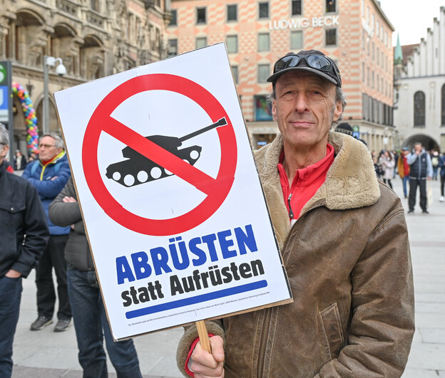 Demonstrant mit einem Plakat, auf dem unter einem Panzer-Verboten-Zeichen 