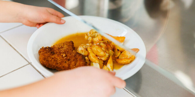 Teller mit Schnitzel, Kartoffeln und Soße an einer Essensausgabe