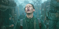 Ein junger Soldat lässt mit geöffnetem Mund den Regen an sich abtropfen