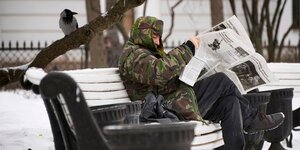 Das Bild zeigt einen Mann auf einer Bank der eine Zeitung liest. Das Bild stammt aus der Ukraine.