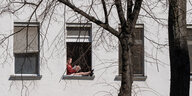 Eine Frau sitzt auf der Fensterbank und liest eine Buch