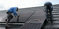 Zwei Männer montieren eine Solaranlage auf ein Hausdach