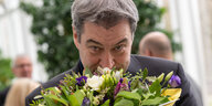 Bayerns Ministerpräsident Söder riecht an einem Blumenstrauß