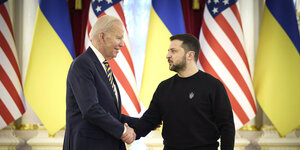 Joe Biden schüttelt Wlodomyr Selenski die Hand vor Flaggen der USA und der Ukraine