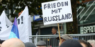 Teilnehmer einer Friedens-Demonstration stehen zu Beginn der Demonstration mit Fahnen und Transparenten zusammen. Auf einem Schild ist die Aufschrift "Frieden mit Russland" zu sehen. Einem bundesweiten Aufruf der Friedensbewegung zu einem Aktionstag gegen den Krieg in der Ukraine und für Abrüstung sind am Samstag in Hamburg Hunderte Menschen gefolgt.