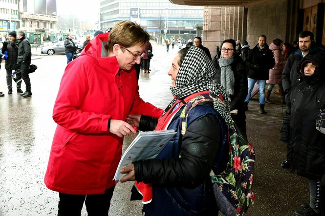 Klara Geywitz spricht mit einer Frau, die ein Tuch um den Kopf gechlungen hat gegen die Kälte und Zeitschriften in der Hand hält