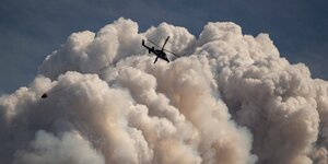 Ein Hubschrauber mit einem Löscheimer fliegt über einem Waldbrand in Lytton, Kanada.