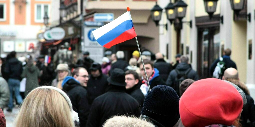 Russische Reisegruppe mit Reiseführer, der ein russisches Fähnchen in die Luft hält