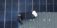 2 Männer platzieren solarmodul auf Dach