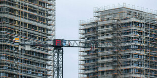 Ein Baukran steht auf einer Baustelle zwischen zwei Neubauten