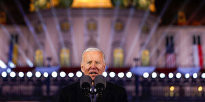 Joe Biden spricht ins Mikrofon vor einer Lichtinstallation