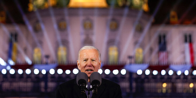 Joe Biden spricht ins Mikrofon vor einer Lichtinstallation