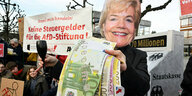 Eine Aktivistin demonstriert vor dem Bundesverfassungsgericht: Sie trägt eine Maske mit dem Gesicht von Erika Steinbach, die große Geldscheine in der Hand hält - im Hintergrund ein Transparent "Keine Steuergelder für die AFD-Stiftung"