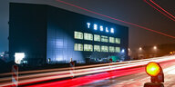 Gebäude von Tesla im Dunkeln mit Lichtstreifen vorbeifahrender Fahrzeuge