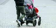 Ein Vater schiebt ein Kleinkind im Kinderwagen