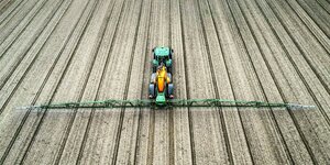 Pflanzenschutzmittel wird mit einem Traktor auf einem Acker aufgesprüht