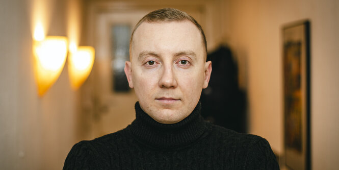 Stanislav Aseyev blickt in einem Wohnungsflur ernst in die Kamera.