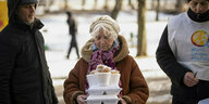 Eine Frau hält mehrere Behälter für warmes Essen in ihren Händen