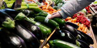 Ein Mann greift eine Zucchini aus der Obstablage