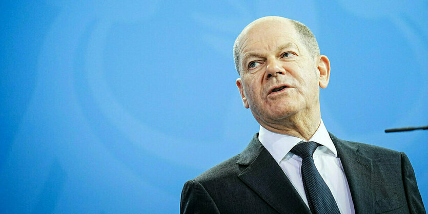 Olaf Scholz vor einer blauen Wand