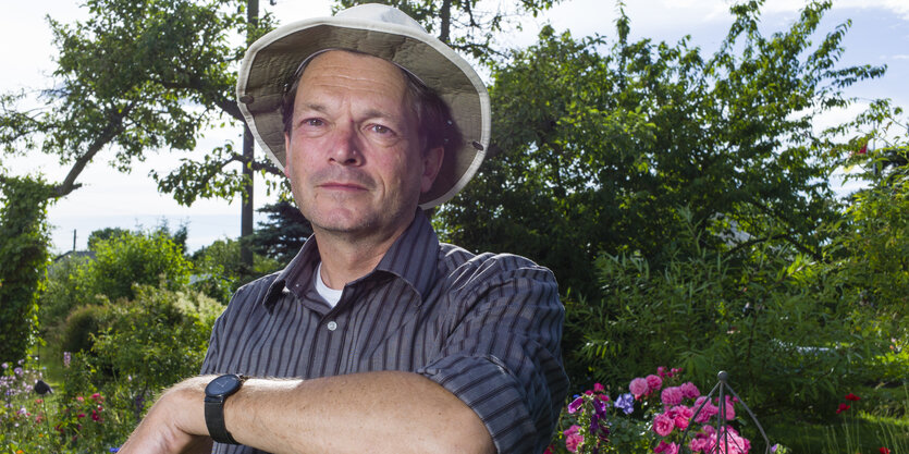 Ein Mann mit Hut steht in einem Garten