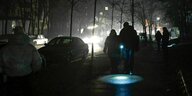 Zwei Menschen gehen mit Taschenlampe durch das dunkle Kiew
