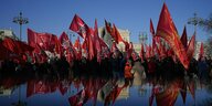 Rote Flaggen der Kommunistischen Partei werden von deren Anhängern während einer Feierstunde durch die Straßen getragen