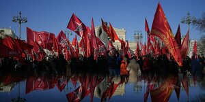 Rote Flaggen der Kommunistischen Partei werden von deren Anhängern während einer Feierstunde durch die Straßen getragen
