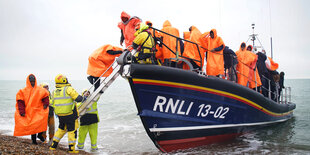 Geflüchtete in einem Boot und Rettungswesten am Körper