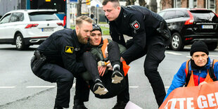 Aktivist der Letzten Generation wird von zwei Polizisten weggetragen