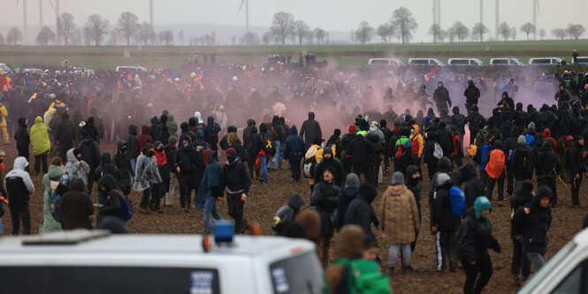 Domonstrant*innen und Polizei begengen sich auf einem Feld bei Lützerath