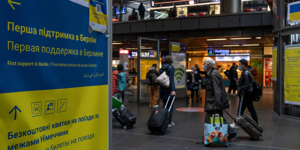 Bahnhof mit Reisenden und Hinweisen für Ukraine-Flüchtlinge