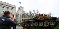 Ein Mann fotografiert ein Panzerwrack vor der russischen Botschaft